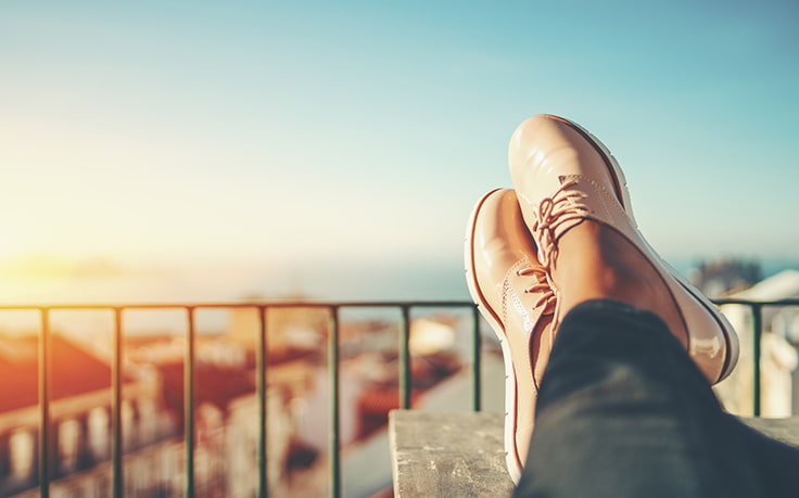 Person auf Balkon, Füße hochlegend